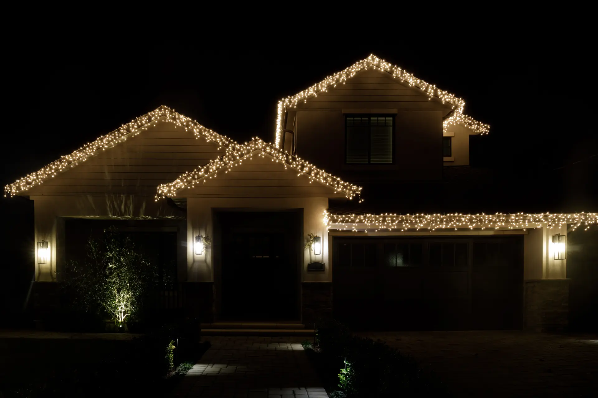 Close-up of warm white lights running evenly along two gables